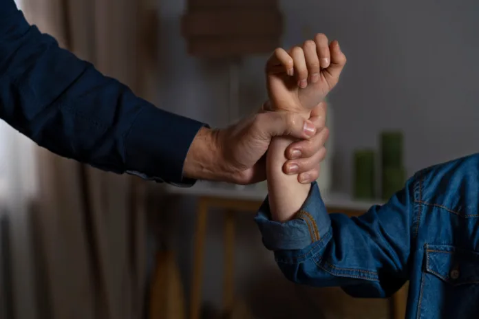 Homem segurando braço de menina