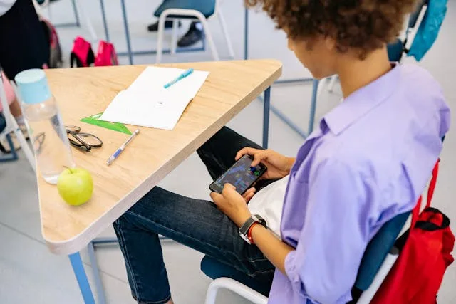 Jovem ao celular em sala de aula