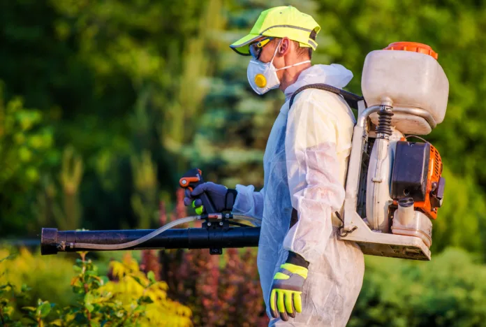 Profissional realizando controle de pragas urbanas com equipamento de pulverização, destacando a atividade como não vinculada à exigência de registro no CREA, conforme decisão do TRF1.