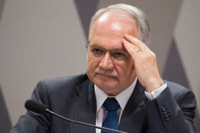 Na foto, o ministro Edson Fachin, do Supremo Tribunal Federal, aparece em momento de concentração durante sessão. Fachin recentemente suspendeu uma decisão do Tribunal de Justiça do Pará que destinava R$ 233 milhões de recursos indígenas Xikrin ao pagamento de honorários advocatícios. A decisão reafirma a competência da Justiça Federal em questões indígenas e garante a proteção de verbas destinadas às comunidades, conforme acordo com a mineradora Vale S/A.