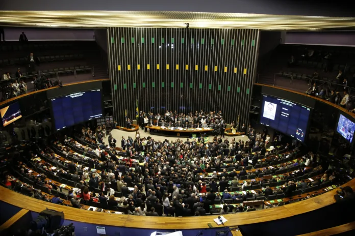 Plenário da Câmara dos Deputados durante sessão legislativa, com parlamentares reunidos para discussão e votação de propostas. Ambiente representativo do processo legislativo brasileiro.