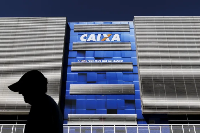 Fachada de agência da Caixa Econômica Federal com slogan 'A vida pede mais que um banco', representando instituição condenada por falha em segurança bancária.