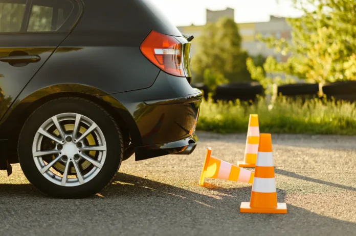 Carro preto realizando manobra próxima a cones de trânsito em uma área aberta, simbolizando exames e testes para obtenção ou renovação da CNH.