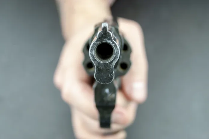 Imagem ilustrativa de uma arma de fogo sendo apontada diretamente para a câmera, representando o caso de disparo ocorrido em um bar do Distrito Federal. Foto conceitual para notícia sobre a condenação de policial civil.