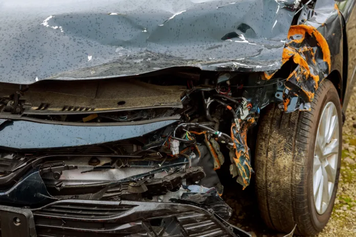 Carro com a dianteira destruída após colisão em rodovia. Veículo sofreu danos graves no capô, para-lama e fiação exposta. Acidente envolveu animal solto na pista, resultando em indenização judicial.